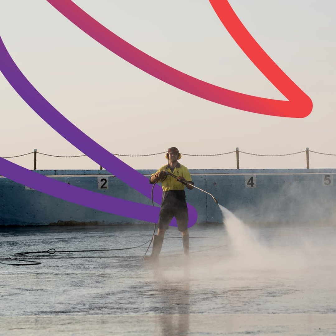Worker cleaning a rockpool with decorative graphic ribbon behind him. He is having way too much fun.