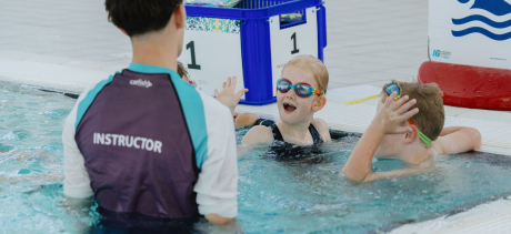 Two children in the pool with a swimming instructor