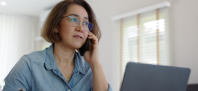 Person speaking on the phone with their laptop infront of them