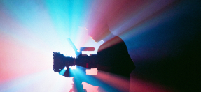 Person filming using technical camera with blue and pink background