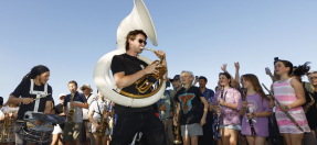 Man playing a large brass instrument surrounded by a crowd of people